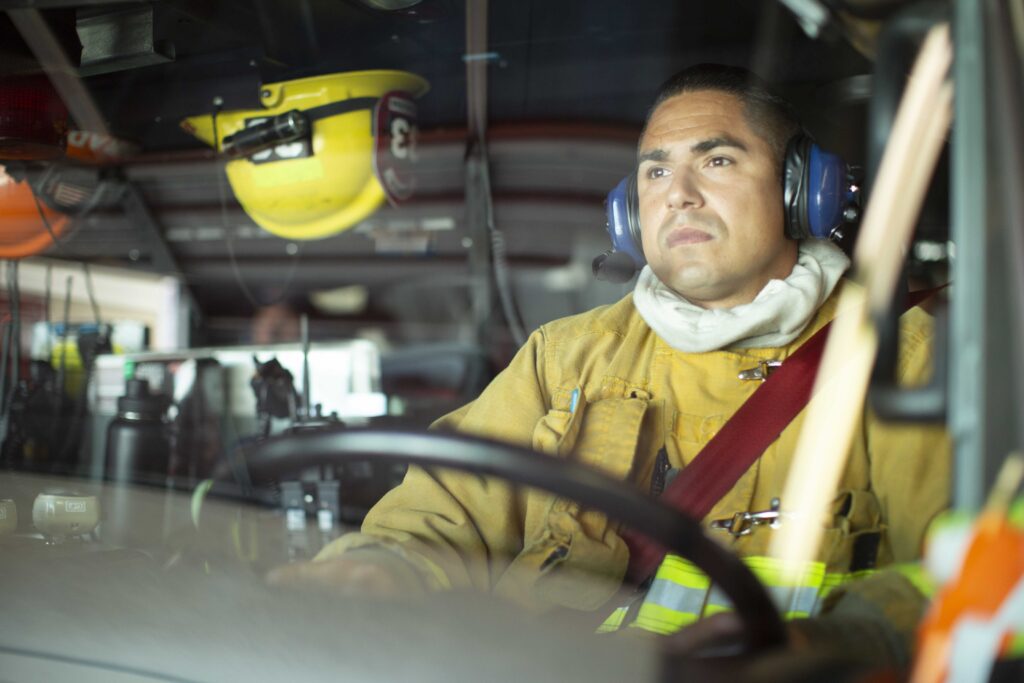 View of firefighter driving fire truck through front window of fire truck.