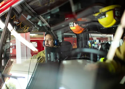 Firefighter sitting inside fire truck.